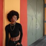 une femme noir entrain de poser sur un mûr